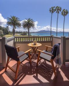 a patio with two chairs and a table and palm trees at Bermagui Beach Hotel in Bermagui