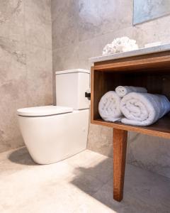 a bathroom with a toilet and towels on a shelf at Bermagui Beach Hotel in Bermagui