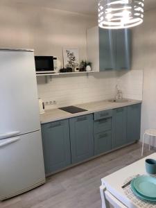 a kitchen with blue cabinets and a white refrigerator at 2х-комнатная на берегу Ангары in Irkutsk