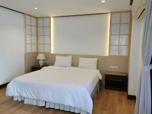 a bedroom with a large bed with white sheets at BaanBusarin Hotel in Hua Hin