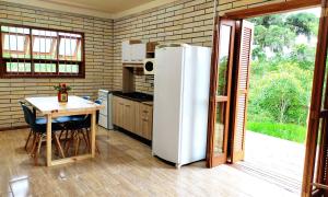 eine Küche mit einem weißen Kühlschrank und einem Tisch in der Unterkunft Sítio da Figueira in Praia Grande