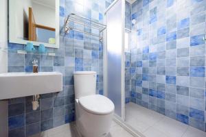 a blue tiled bathroom with a toilet and a sink at 夏天民宿 in Magong