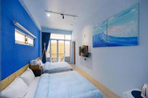 1 dormitorio con 2 camas y pared azul en 夏天民宿, en Magong