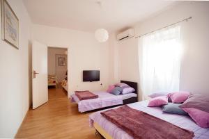1 dormitorio con 2 camas y almohadas rosas en Dalmatian Garden - FREE parking - city centre, en Šibenik