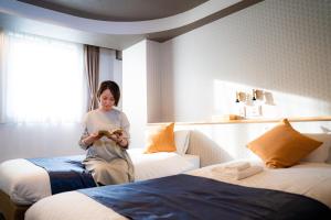 a woman sitting on two beds in a hotel room at Hotel S-Presso Central in Osaka