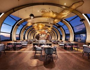un restaurante con mesas, sillas y ventanas grandes en Golden Tulip Holland Resort Batu en Batu