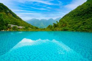 a pool of blue water with mountains in the background at Mai Chau Mountain View Resort in Mai Chau