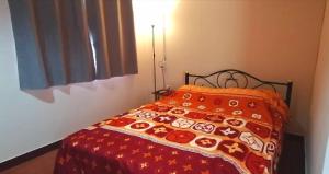 1 dormitorio con 1 cama con edredón rojo en บ้านสวนยายชุ่ม/bannsuanyaychum, en Lampang
