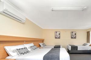 1 dormitorio con 2 camas con sábanas blancas en Kiama Motel 617, en Kiama
