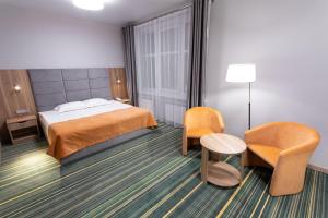 a hotel room with a bed and two chairs at ParkCity Hotel in Chelyabinsk