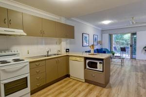 a kitchen with white appliances and a living room at Townsville Southbank Apartments in Townsville