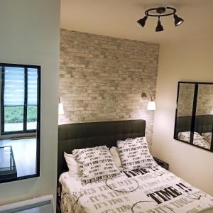 a bedroom with a brick wall and a bed with pillows at Détente & Jardin By Beds4Wanderlust - Charmant T2 avec Jardin - Gare Plaisir-Grignon, Versailles 20km in Plaisir