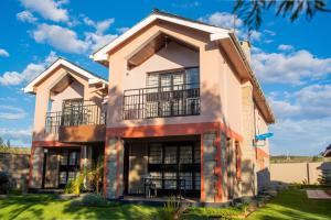 a house with two balconies on a lawn at El Sueno Homestay in Naivasha