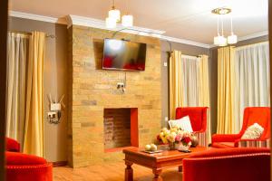 a living room with a stone fireplace and red chairs at El Sueno Homestay in Naivasha