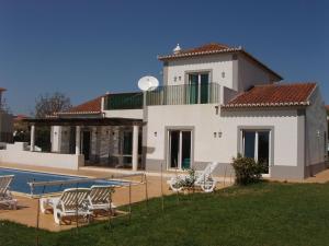 ein weißes Haus mit einem Pool und Stühlen in der Unterkunft Villa Castelos, Quelfes, Eastern Algarve private pool in Olhão