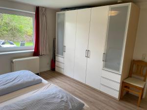 1 dormitorio con armarios blancos, 1 cama y ventana en Bungalow 1, en Wyk auf Föhr