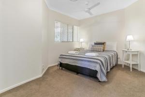 a white bedroom with a bed and a window at Cosy apartment with ocean views, Sunshine Beach in Sunshine Beach +6 photos