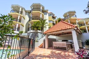 an apartment building with a patio and a bench at Cosy apartment with ocean views, Sunshine Beach in Sunshine Beach