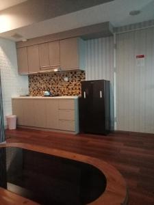 a kitchen with a black refrigerator in a room at Apartemen Grand Kamala Lagoon Bekasi By Cicie Room in Pekayon Satu