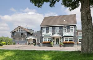 ein großes graues Gebäude mit Blumen davor in der Unterkunft Hotel Restaurant Fischer in Remscheid