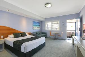 a hotel room with a bed and a table and chairs at Shellharbour Village Motel in Shellharbour