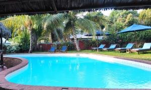 uma piscina com cadeiras azuis e palmeiras em Clair de Lune em Ambatoloaka