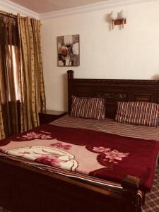 a bedroom with a large bed with a red comforter at Happy Stay Guest House in Abbottābād