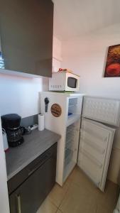 a small kitchen with a microwave on top of a refrigerator at Studio vue mer Le Colibri in Sainte-Anne