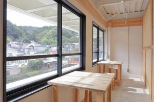 Habitación con ventanas grandes y mesa de madera. en ITJ Base Shuzenji, en Shuzenji