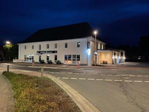 a white building on the side of a street at night at Central Hotel Wagenfeld in Wagenfeld