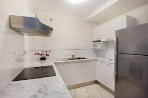 a kitchen with a refrigerator, stove, sink and microwave at Surfers International Apartments in Gold Coast
