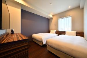 a hotel room with two beds and a television at Hotel WBF Grande Hakata in Fukuoka