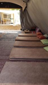 um grupo de almofadas sentado dentro de uma tenda em חאן בכפר במשק בלה מאיה - האוהל em Nevatim