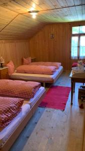 a room with three beds and a table in it at Berghaus Iffigenalp in Lenk