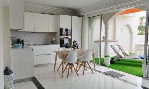 a kitchen with white cabinets and a table and chairs at Luxury apartment, comfort and relax, views of the pool in Puerto de la Cruz
