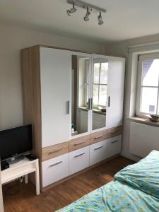 a bedroom with a large white cabinet and a television at Ferienhaus SPO 54 grad in Sankt Peter-Ording