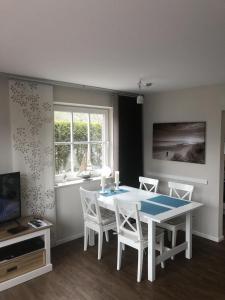 a dining room with a white table and chairs at Ferienhaus SPO 54 grad in Sankt Peter-Ording