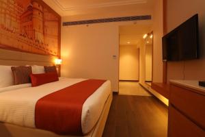 a hotel room with a bed and a flat screen tv at Regenta Central Udaipur, Court Circle in Udaipur