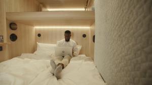 a man sitting on a bed using a laptop at CAB20 in Hamburg