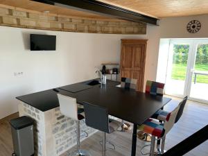 Gîte Manulau في Turqueville: غرفة طعام مع طاولة سوداء وكراسي