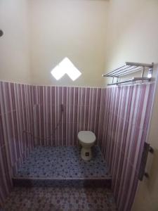 a bathroom with a toilet in a shower with purple stripes at OYO 90731 E-kreasi Home in Sekayu