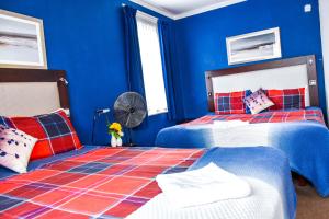 a blue bedroom with two beds and a fan at Gatwick Castle B&B in Horley