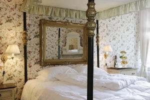 a bedroom with a bed with a mirror on the wall at Hotel Frederiksminde in Præstø