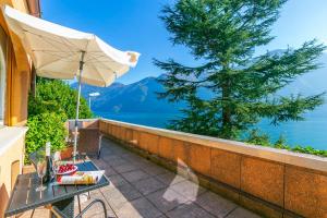 a table with an umbrella on a balcony with a view of the water at Apartments Gelsomino, Orchidea and Magnolia - Happy Rentals in Castagnola
