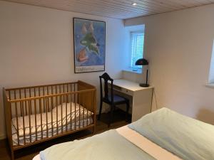 a bedroom with a crib and a desk with a chair at Hegnsly in Odder