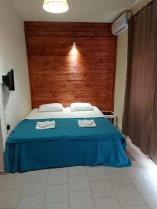 um quarto com uma cama azul e uma cabeceira em madeira em Nefeli Apartments Ορεστιάδα em Orestiada