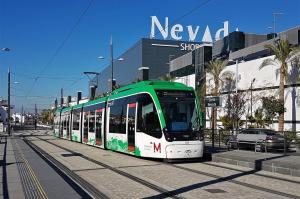 a green and white tram on a city street at Spacious Apartment in Armilla