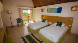 a hotel room with two beds and a balcony at Shams Alam Beach Resort in Abū Ghuşūn