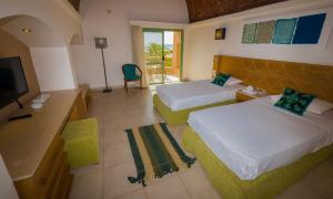 a hotel room with two beds and a television at Shams Alam Beach Resort in Abū Ghuşūn