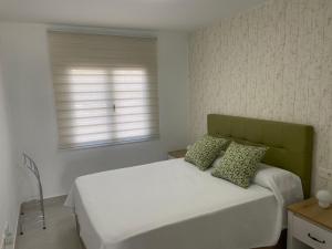 - une chambre avec un lit blanc et une fenêtre dans l'établissement Piso tranquilo,piscina comunitaria.Zona turística, à Costa Teguise